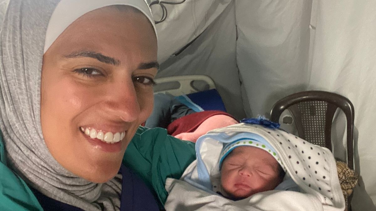  Jordanian obstetrician Asil Al-Jallad carrying a new born baby that she helped deliver in Gaza during the ongoing war (Supplied)